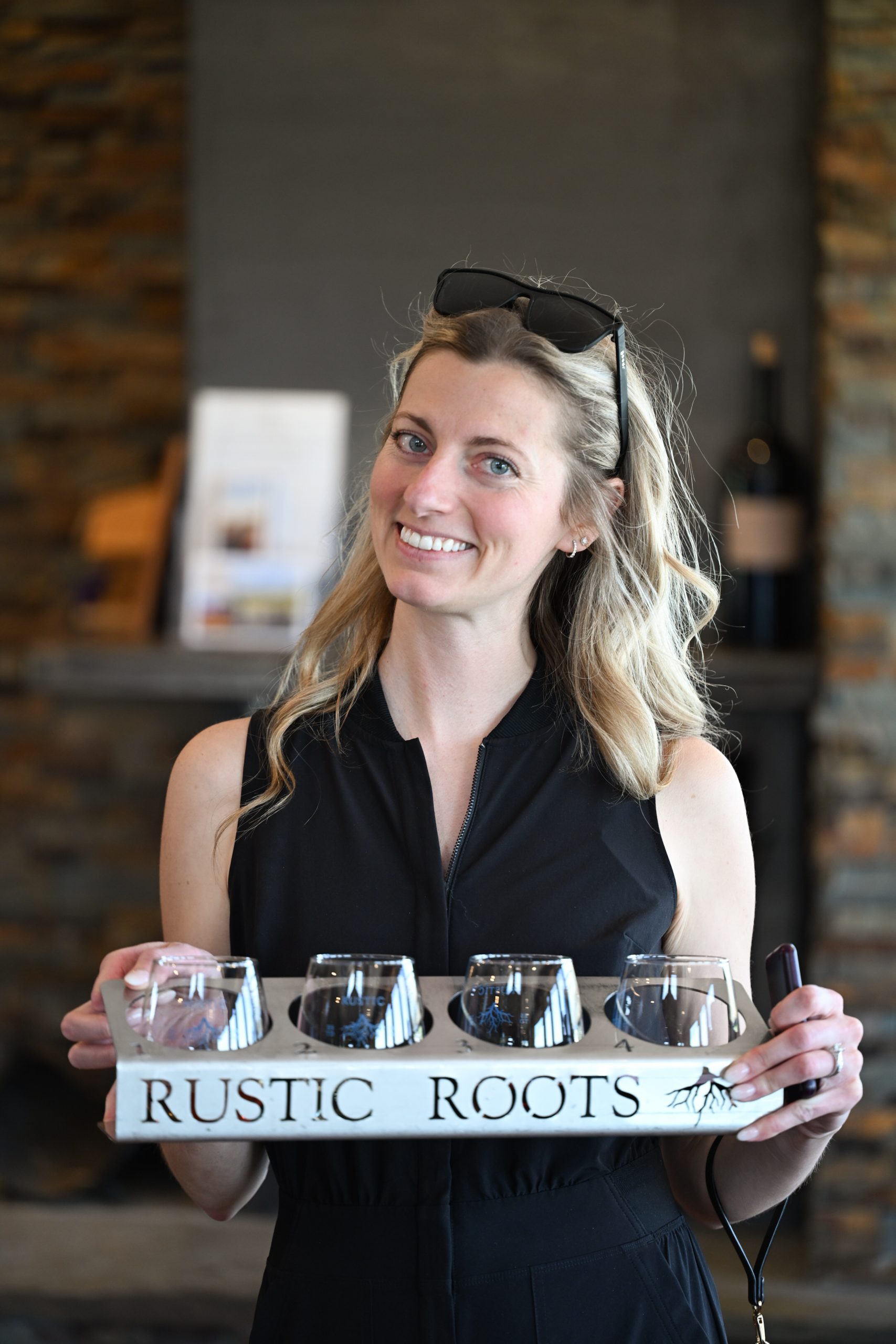 Jacki campbell holding flight of wines at rustic roots
